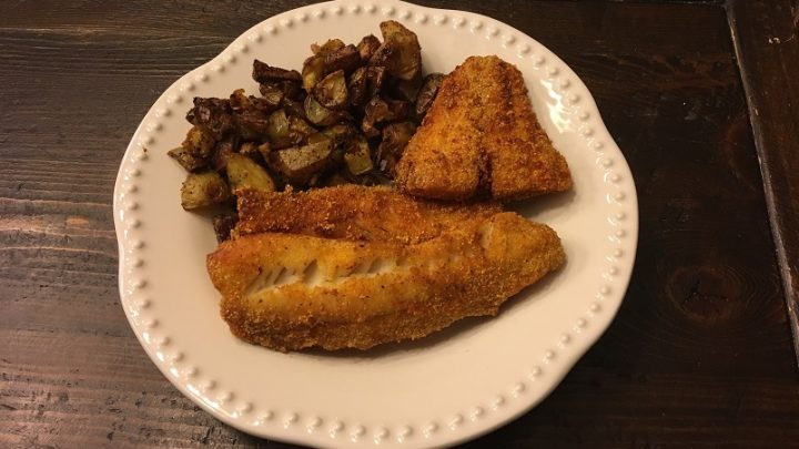 Fried walleye and roasted potatoes on a dinner plate