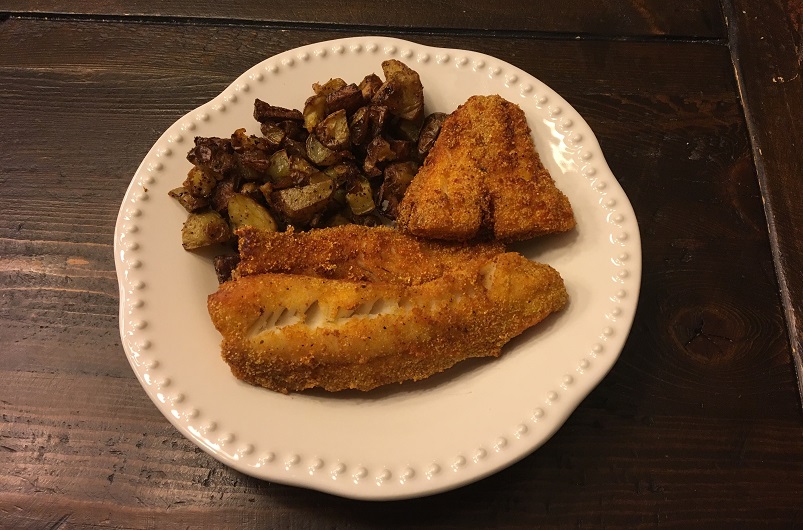 Fried walleye and roasted potatoes on a dinner plate