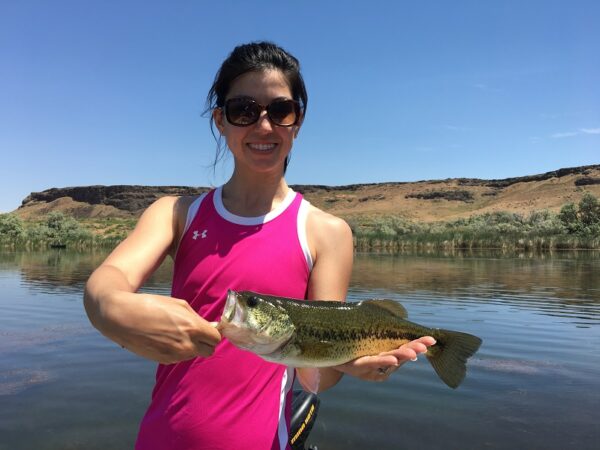 Happy female student holding a largemouth bass