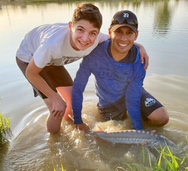 A teenaged boy and Jordan Rodriguez holding a white sturgeon.
