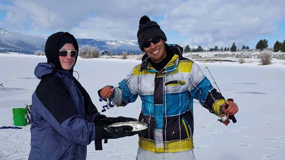 Jordan Rodriguez and Justin Maxwell show off a rainbow trout that nearly stole a rod on an ice fishing trip.