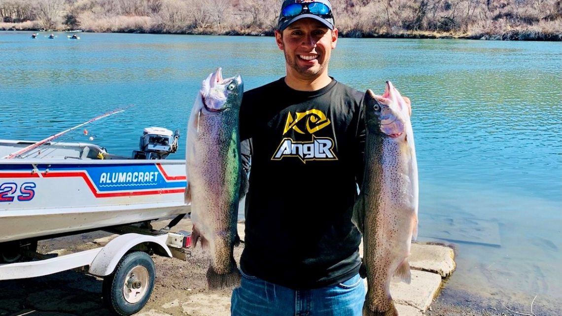 Jordan Rodriguez holds two large rainbow trout caught in the Snake River