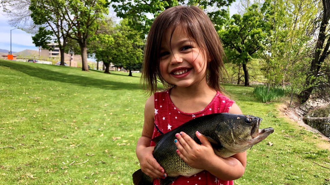 Quinn Rodriguez holds on tight to a big largemouth bass caught in a local pond.