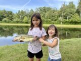 Two young girls holding a largemouth bass at a pond in northern Michigan.