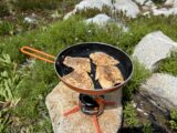 Filleted trout in a frying pan on a camp stove.