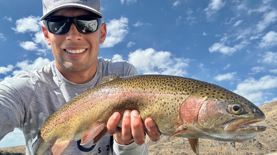 Jordan Rodriguez holding a 23-inch rainbow trout caught in a remote Idaho desert reservoir.